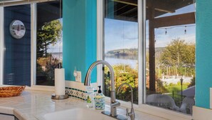 Une cuisine équipée d’un évier, d’une fenêtre donnant sur un lac et d’un thermostat fixé au mur.