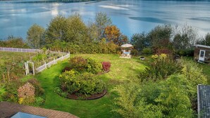 Un jardin agrémenté d’un belvédère, d’une zone délimitée par une clôture et offrant une vue sur un lac.