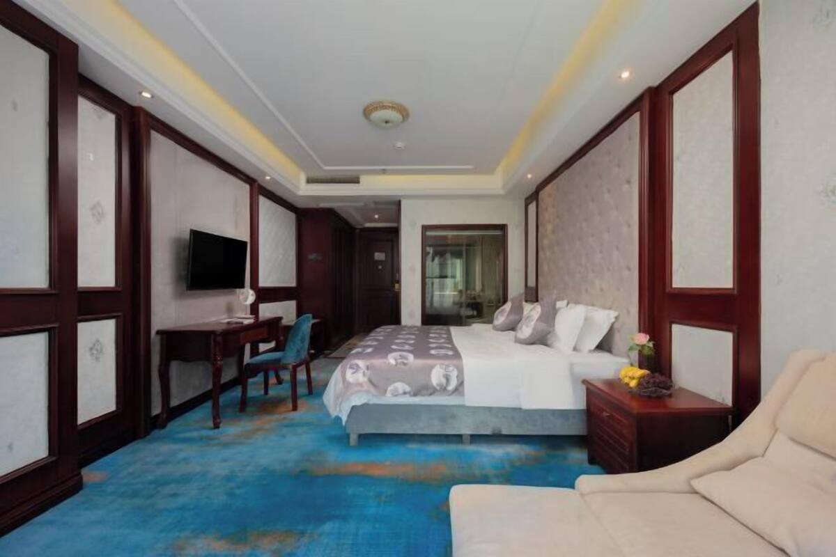 Ein Hotelzimmer mit Bett, Nachttisch, Sessel, Fernseher und Blick ins Freie.