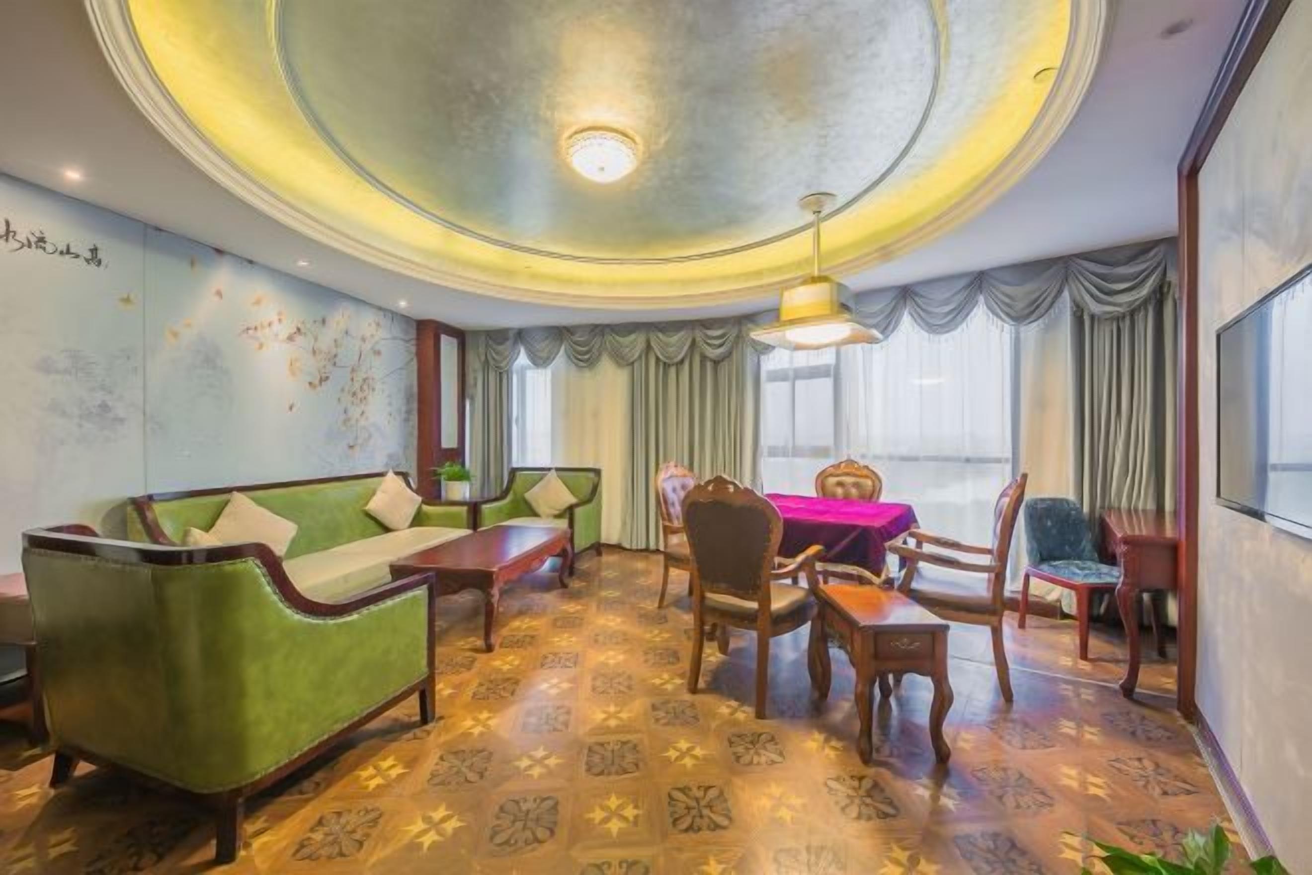 A room with a green sofa, wooden chairs, a dining table, and a large window with curtains.