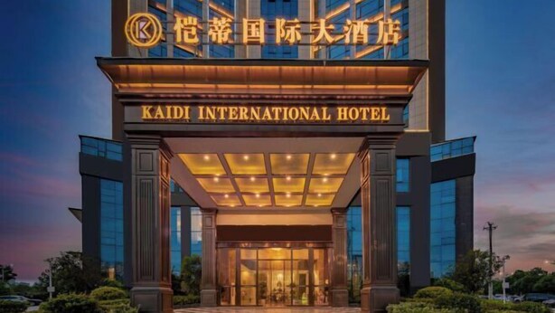 L’entrée de l’hôtel international Kaidi, avec sa façade moderne, ses grandes fenêtres en verre et son hall d’entrée bien éclairé.
