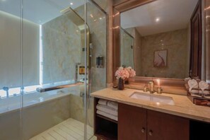 Ein modernes Badezimmer mit Duschkabine aus Glas, Marmorplatte und großem Spiegel.