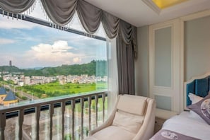 Une chambre d’hôtel dotée d’une grande fenêtre donnant sur un paysage urbain et des espaces verts.