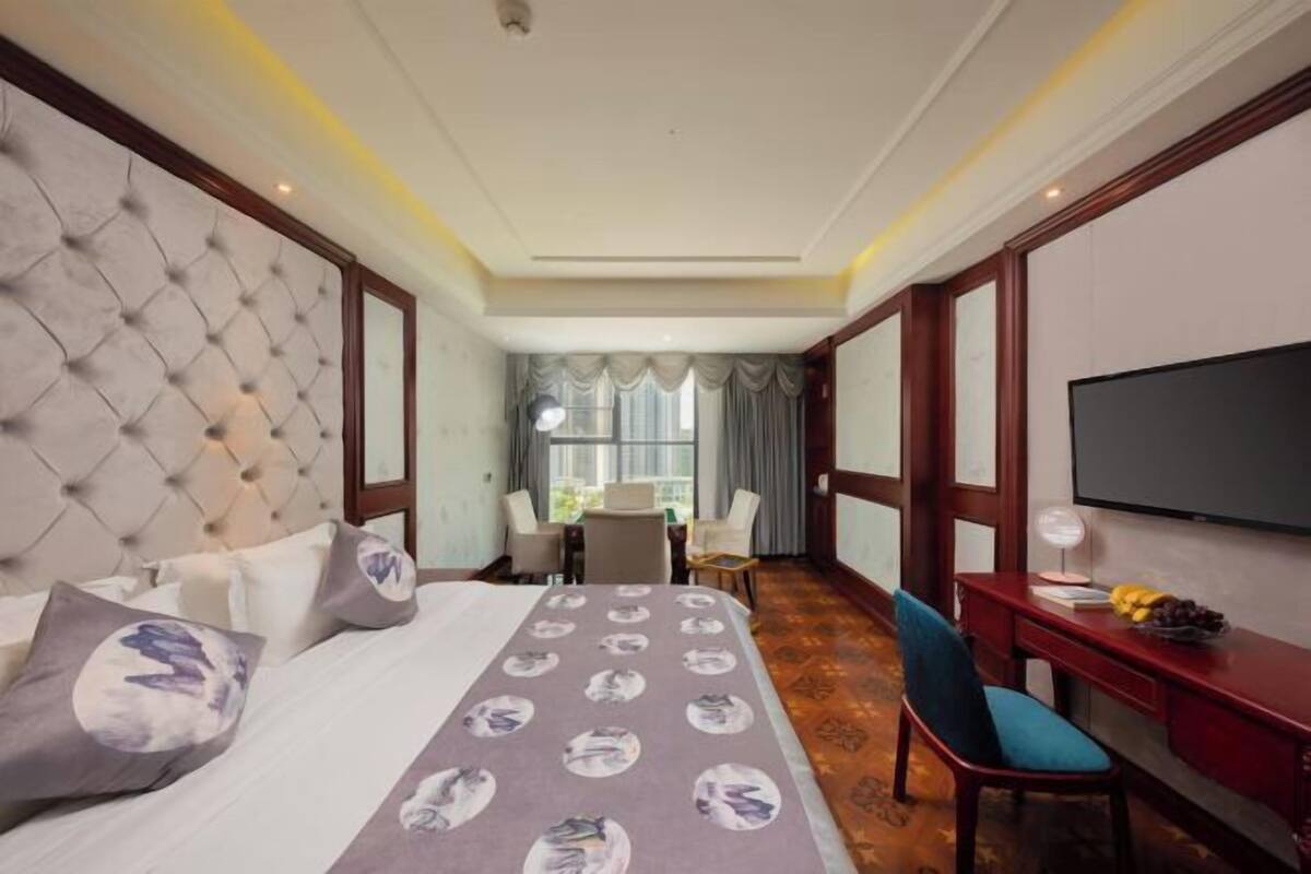 Ein Hotelzimmer mit einem großen Bett, einem Schreibtisch mit Fernseher und Blick ins Freie.