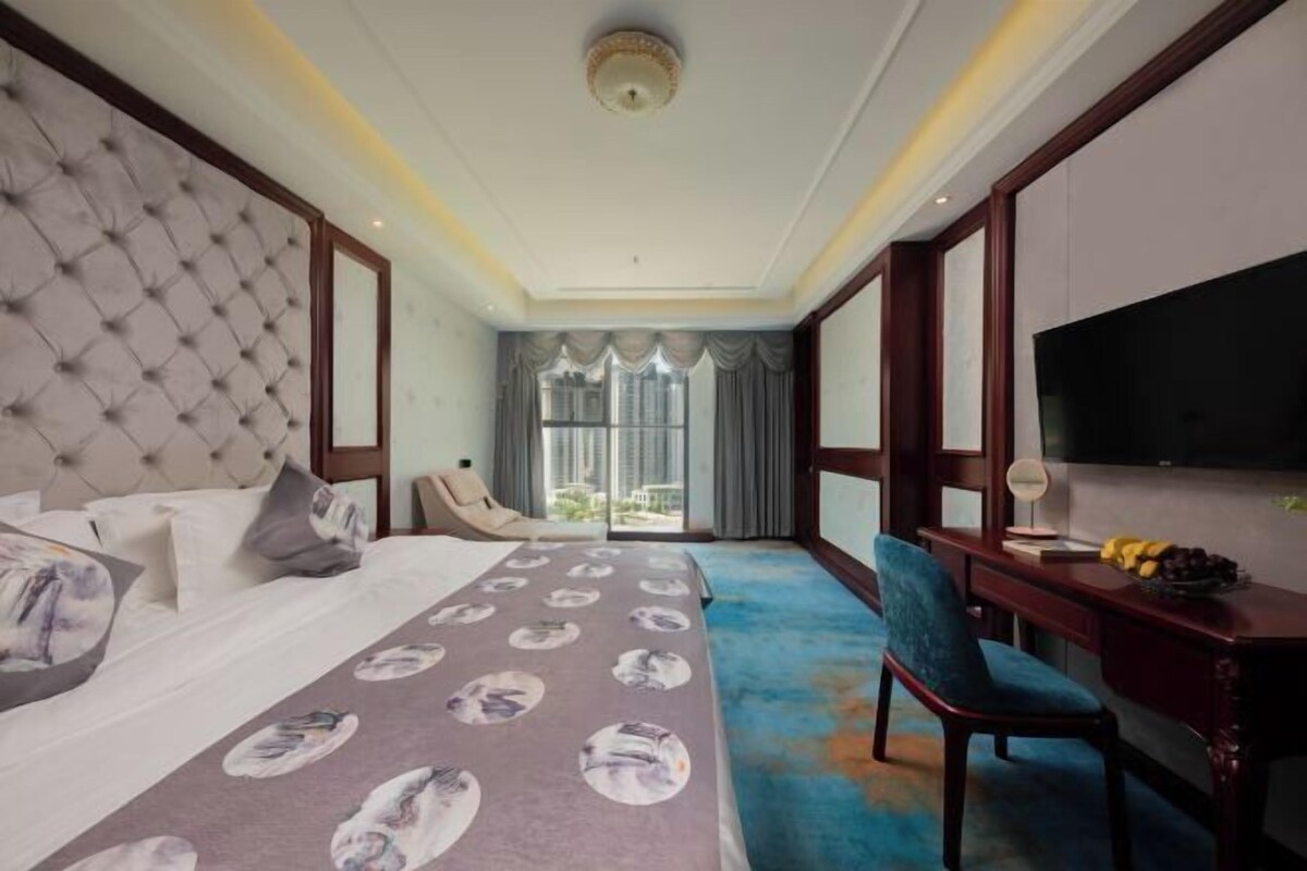 Une chambre d’hôtel avec un grand lit, un bureau avec une chaise, une télévision et une vue sur l’extérieur.
