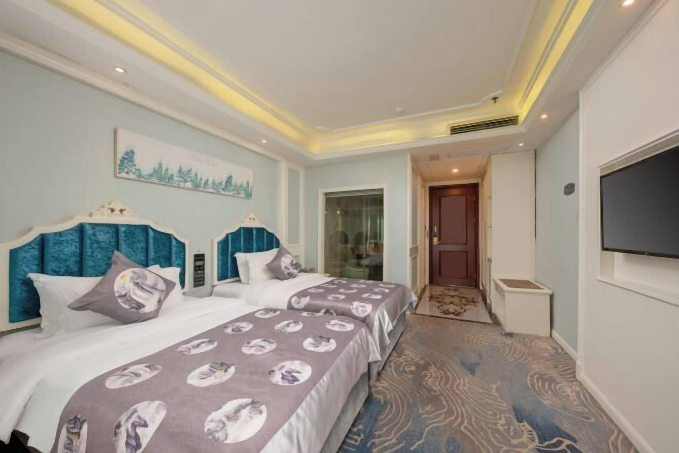 Una habitación de hotel con una cama grande, televisión y un cuadro en la pared.