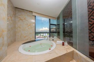 Un baño moderno con una bañera grande, cabina de ducha de vidrio y vistas a un paisaje urbano.