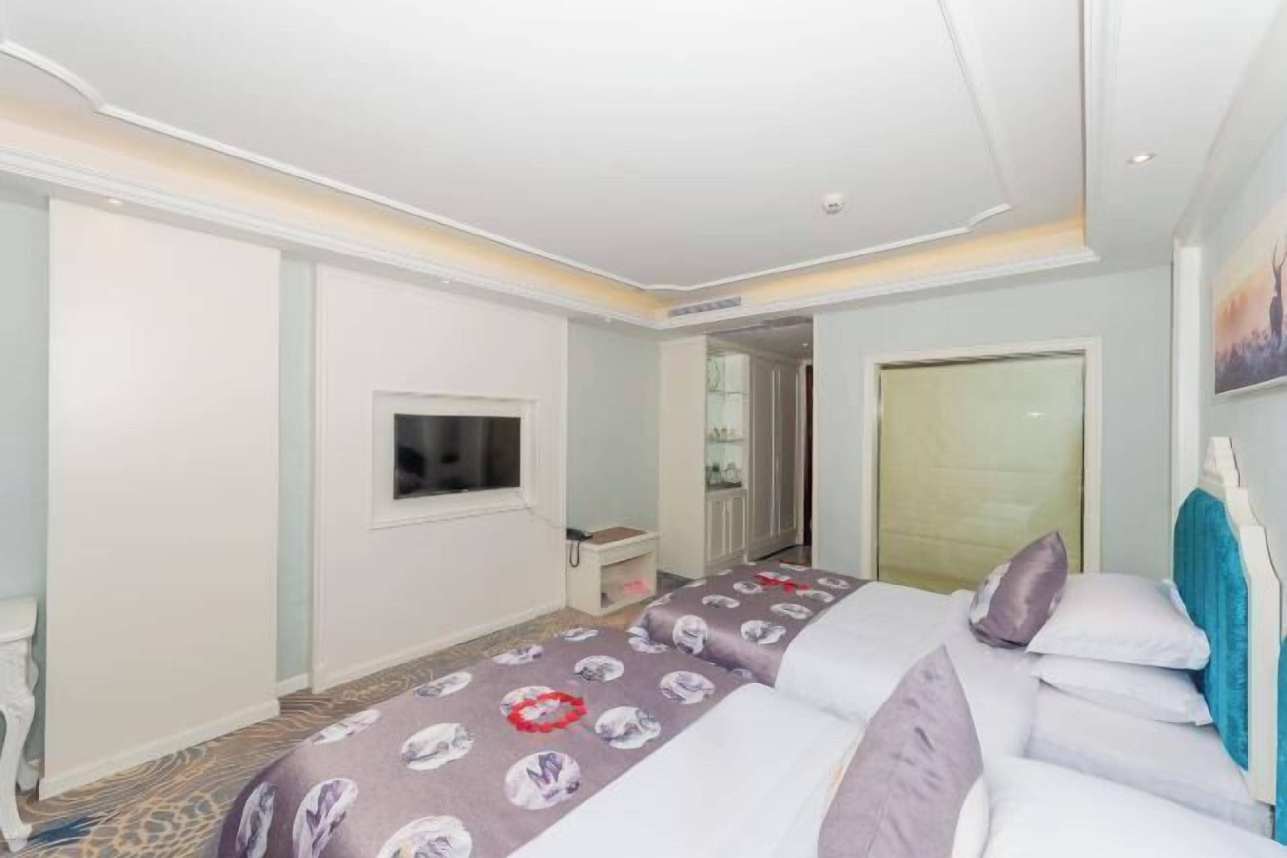 Ein Hotelzimmer mit Bett, Fernseher, Kleiderschrank und einem durchgegangenen Tür sichtbaren Badezimmer.