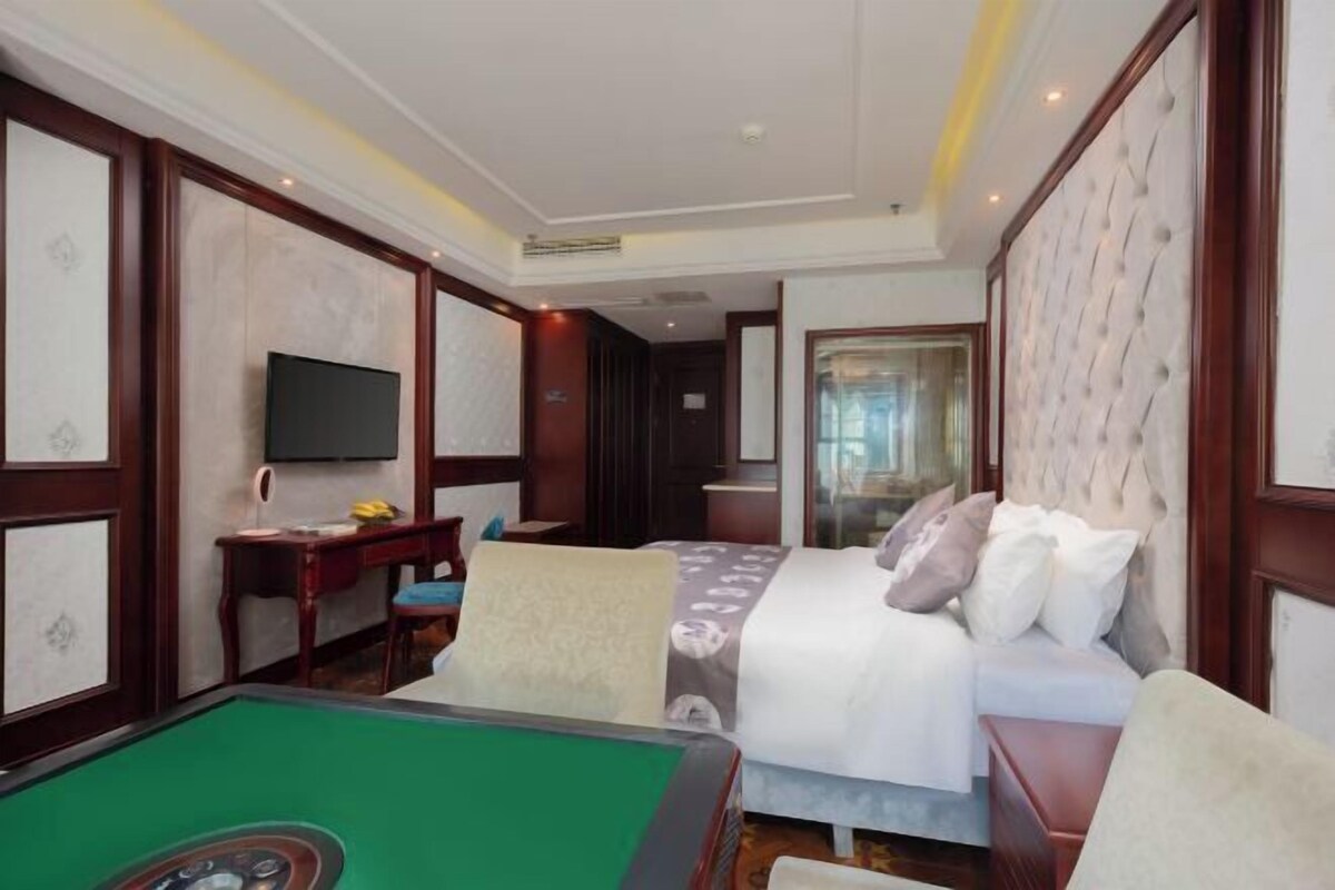 Une chambre d’hôtel équipée d’une table de billard, d’un lit, d’un bureau et d’une télévision.
