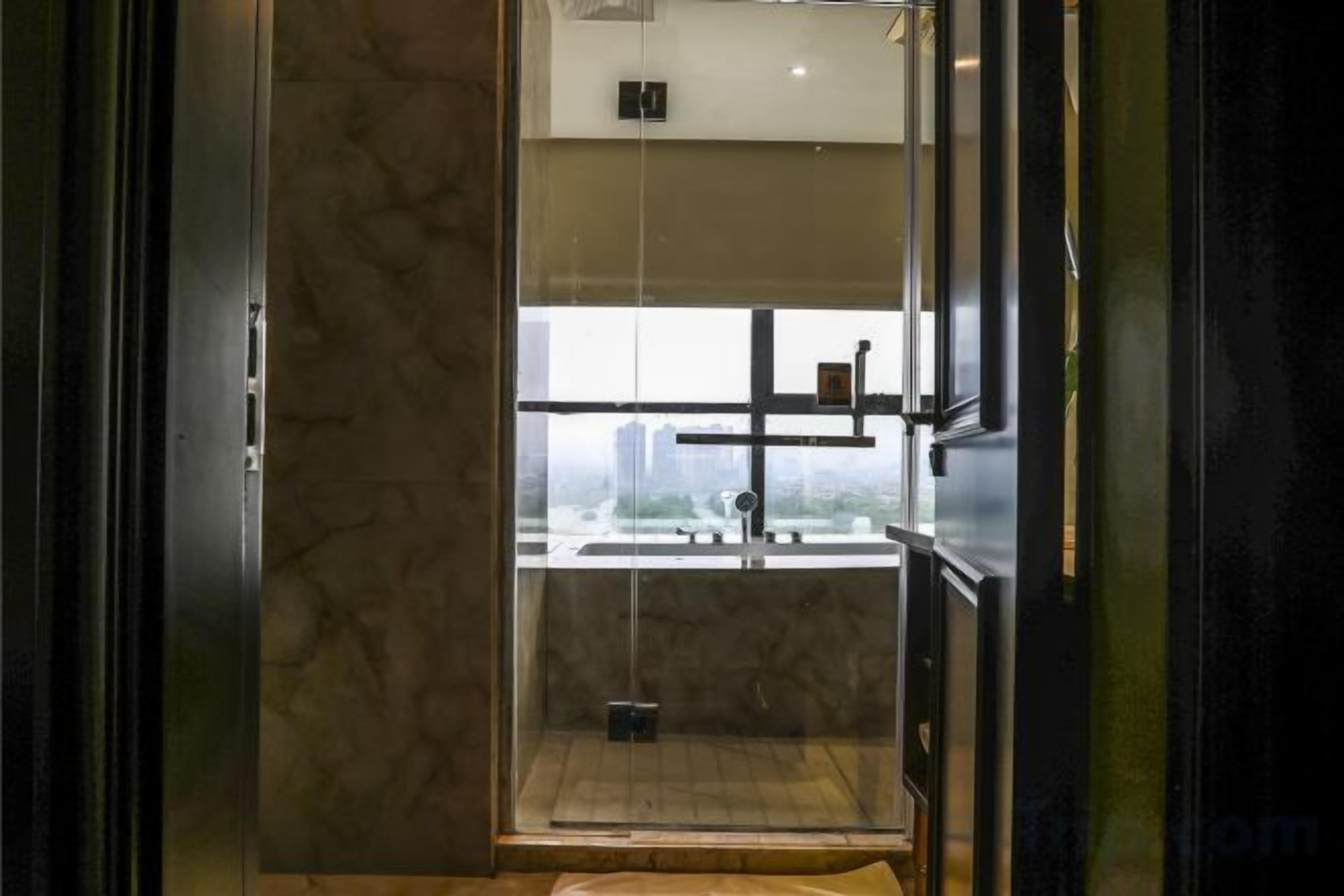 A modern bathroom with a glass enclosure, a visible shower area, and a view of the cityscape.