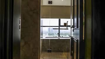 A modern bathroom with a glass enclosure, a visible shower area, and a view of the cityscape.