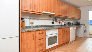 A kitchen with wooden cabinets, a built-in oven, a dishwasher, and a tiled backsplash. - Tigre - Jesus Pobre, Costa Blanca (Jesus Pobre)