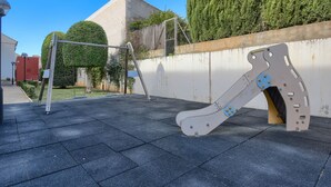 A playground with a slide and swings, surrounded by a concrete wall and greenery. - Tigre - Jesus Pobre, Costa Blanca (Jesus Pobre)