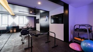 A modern gym with exercise equipment, a wall-mounted sign, and a rack with fitness balls. - Atour Hotel (Ningbo)