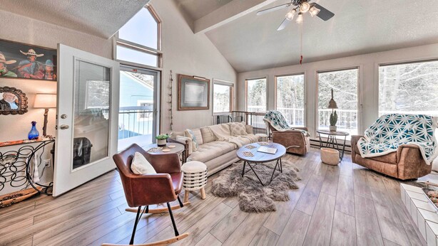 A spacious living room with a high ceiling, large windows, a ceiling fan, and a cozy seating area with a sofa and chairs. - Bright Cloudcroft Condo w/ Game Room + Deck! (Cloudcroft)