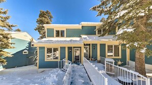 A two-story house with a snow-covered front yard and a white fence. - Bright Cloudcroft Condo w/ Game Room + Deck! (Cloudcroft)