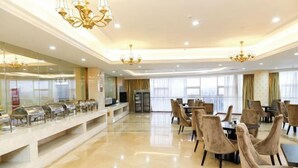 Spaziosa sala da pranzo d'albergo con un'ampia linea di buffet, numerosi tavoli e eleganti lampadari.