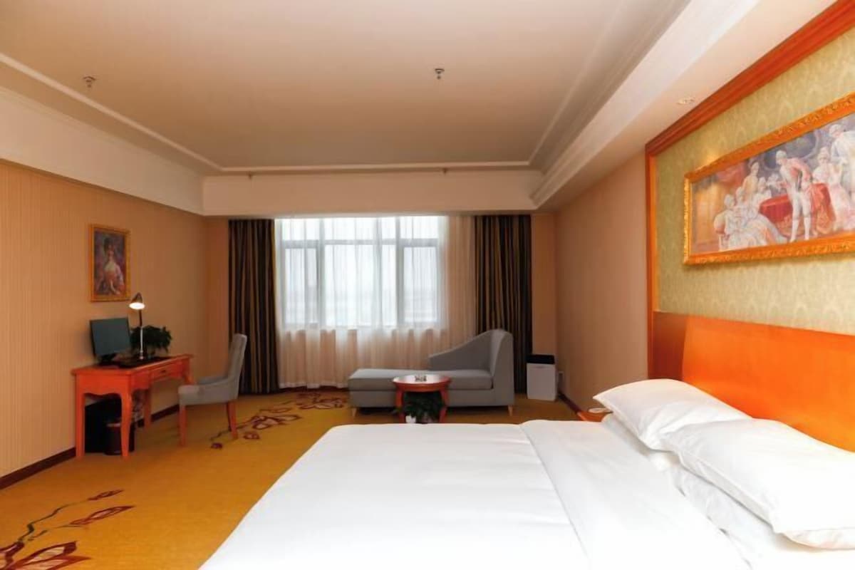 Una habitación de hotel con una cama grande, un escritorio con una silla, un sofá y una mesita.