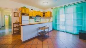 A compact kitchen with wooden cabinets, a small refrigerator, and a tiled floor.