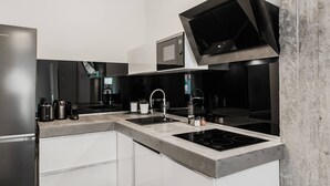 A modern kitchen with a built-in microwave, a stainless steel refrigerator, a double sink, and a gas stove.