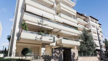 Un immeuble résidentiel à plusieurs étages, doté de balcons, de piliers en pierre et de plantes en pot.