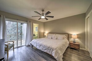 Relax in this serene bedroom with a large bed, ceiling fan, and comfortable chair.