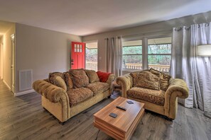 Relax in this inviting living room with plush sofas, a coffee table, and large windows.