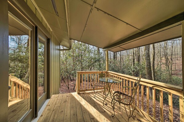 Enjoy a forest view from this deck with a glass table and comfortable seating.