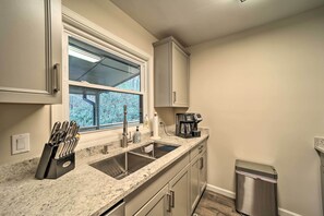 Enjoy cooking in this well-equipped kitchen with a sink, cabinets, and coffee maker.