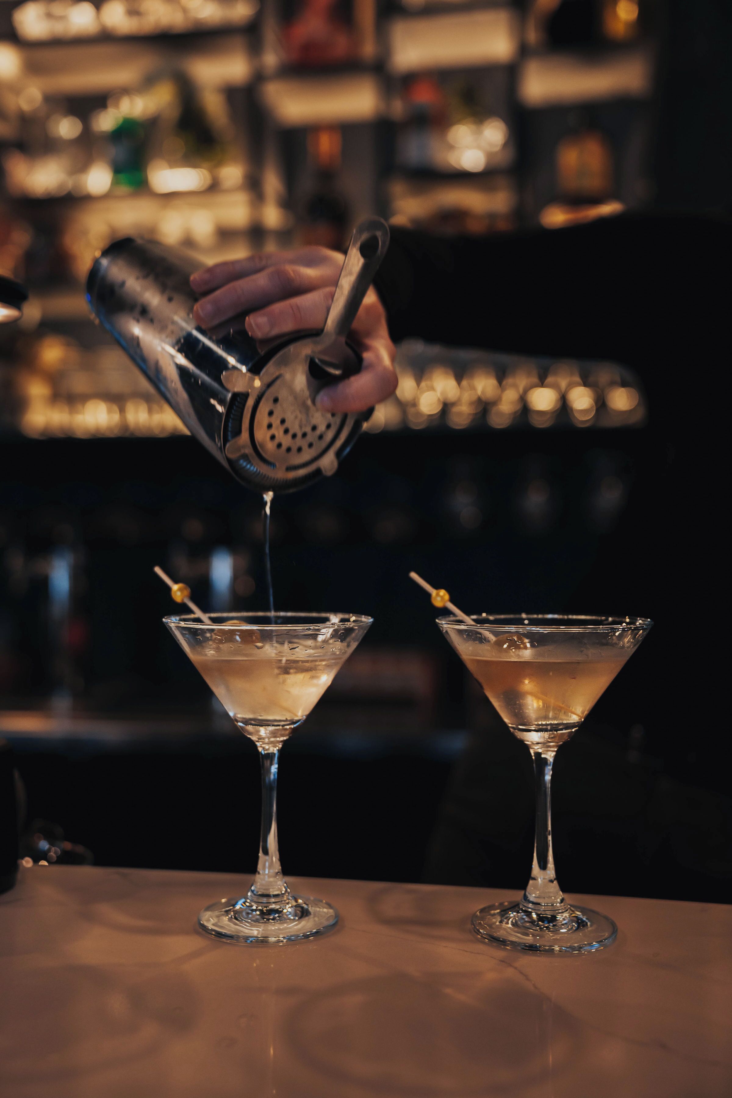 Un barman sirviendo una bebida en una copa de martini.