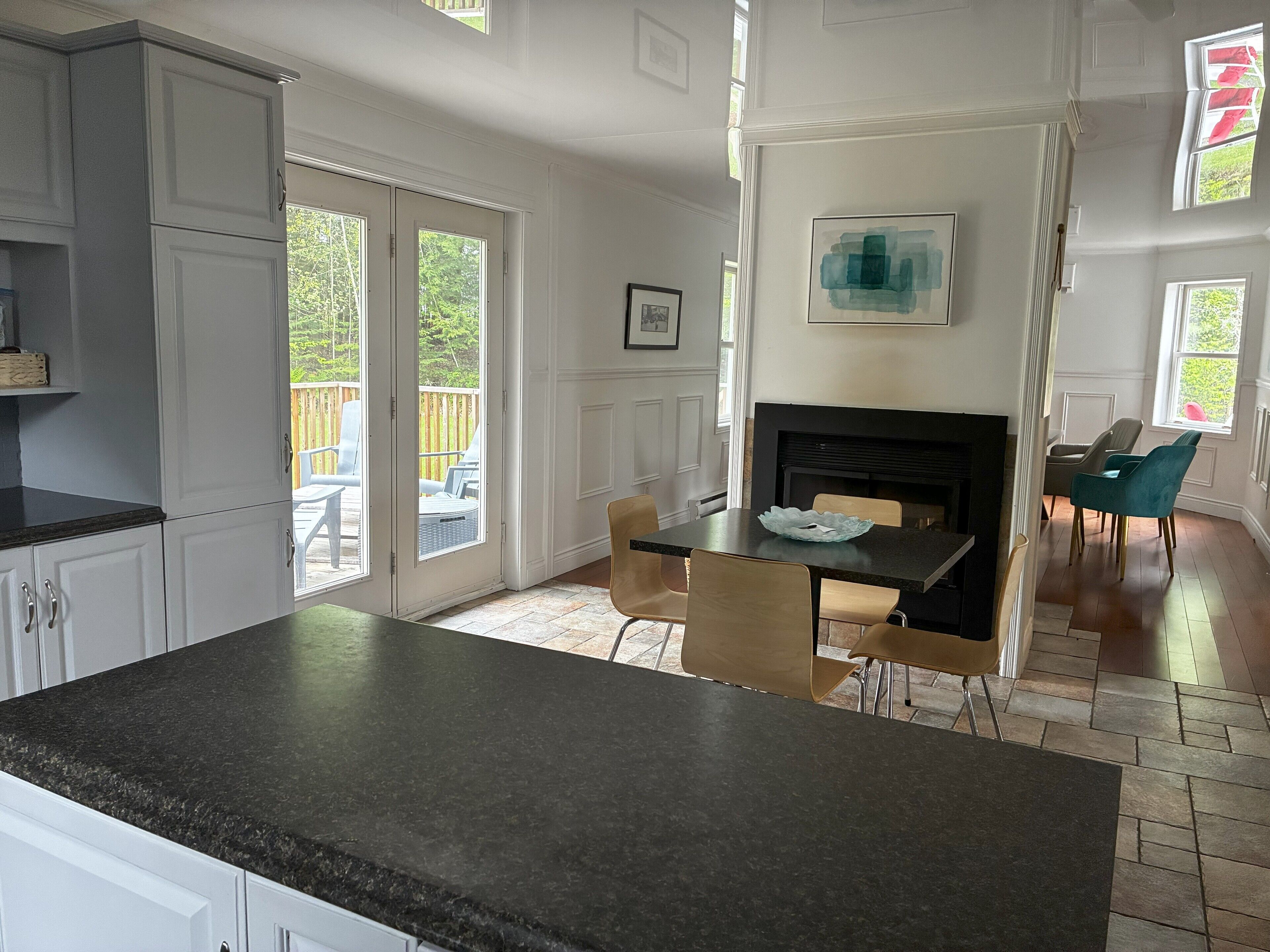 A kitchen with a black countertop, white cabinets, and a dining area with a table and chairs.