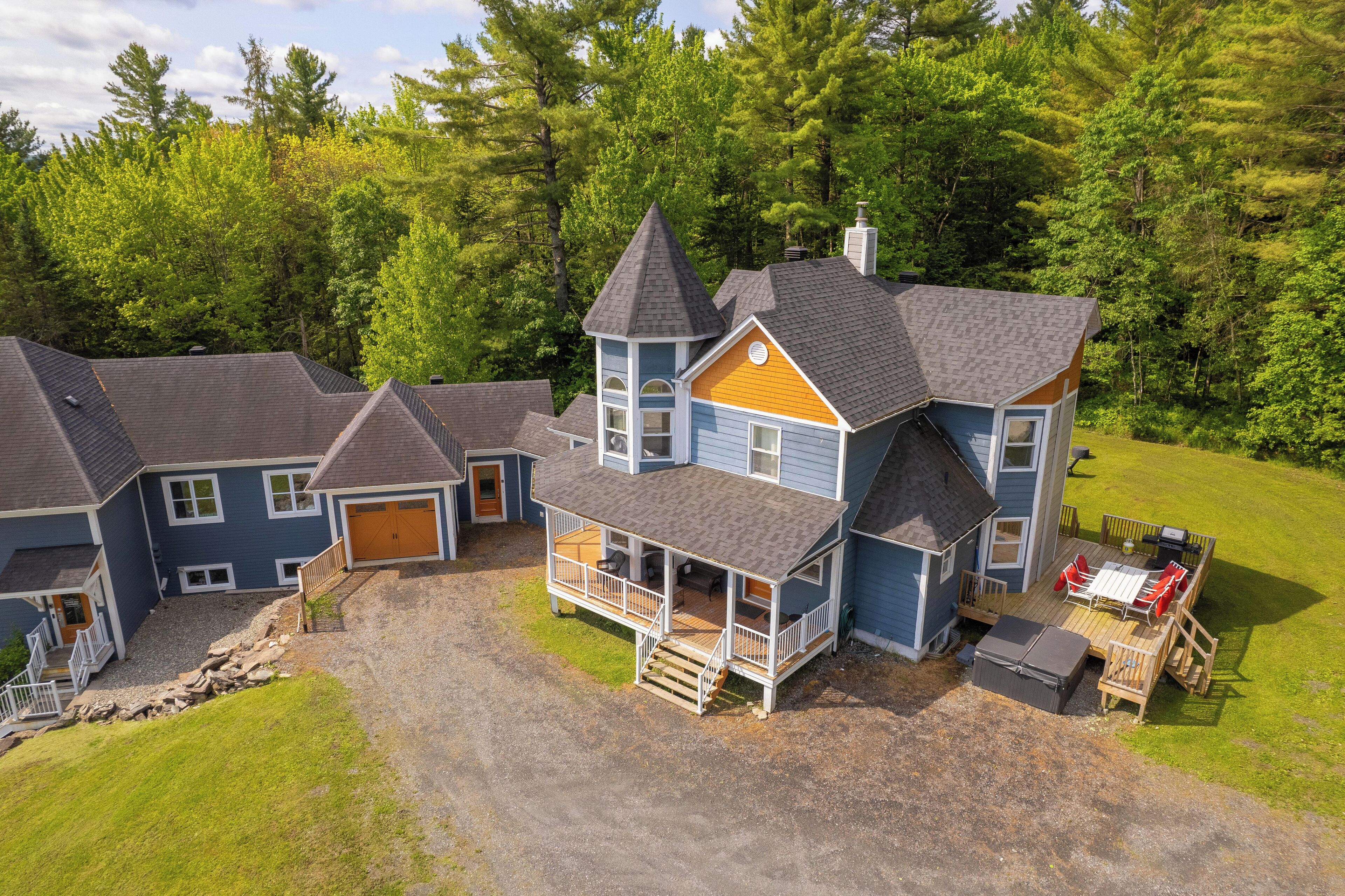 A large, multi-story house with a prominent tower, a covered porch, and a deck with outdoor furniture.