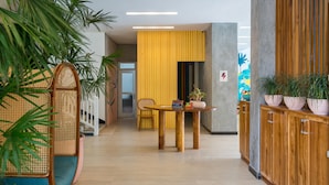 A modern interior with a wooden table, a yellow accent wall, and potted plants. - Outpost Weligama Beachfront (Weligama)