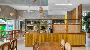A cafe with a wooden counter, seating area, and ceiling fans. - Outpost Weligama Beachfront (Weligama)