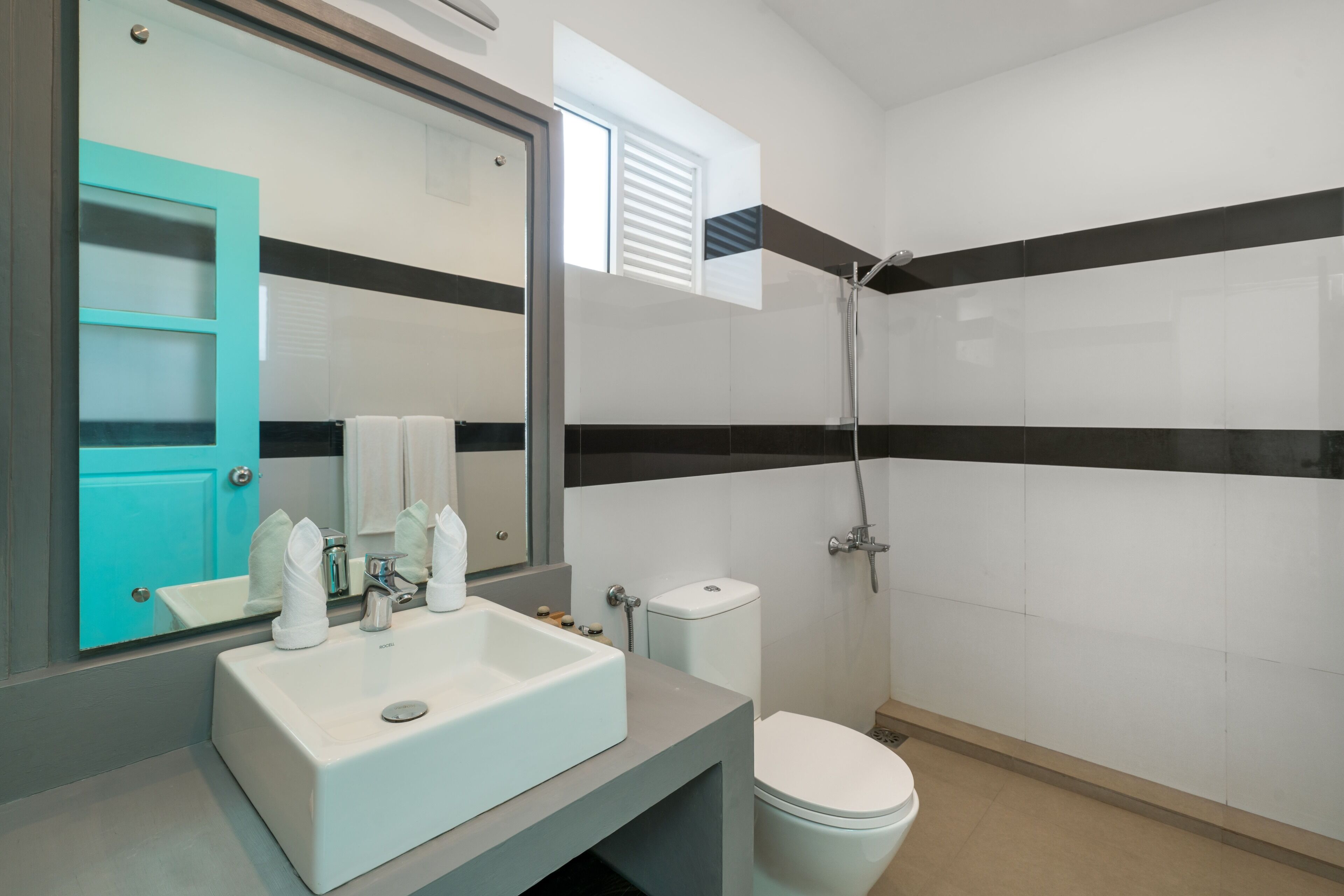 Un baño moderno con un lavamanos blanco, inodoro y ducha.