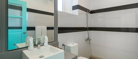 A modern bathroom with a white sink, a toilet, and a shower.