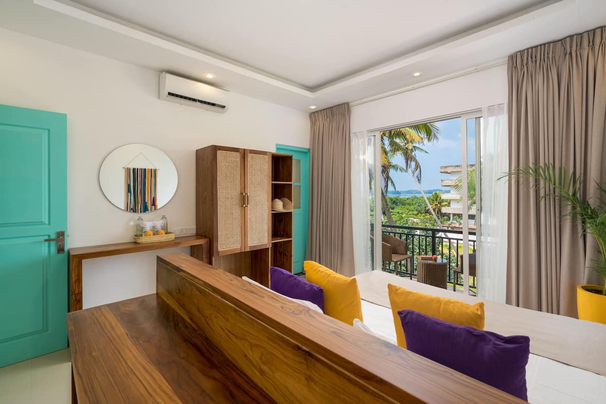 A modern room with a wooden bench, a round mirror, and a view of the outdoors.