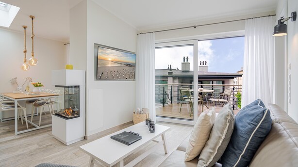 A modern living room with a fireplace, a dining area, and a balcony with a view of the city. - Quartier 7, App. 16, Germany (Heringsdorf)