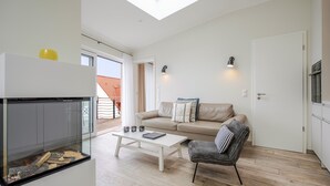 A modern living room with a glass fireplace, a sofa, a coffee table, and a chair. - Quartier 7, App. 16, Germany (Heringsdorf)