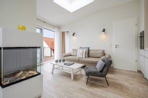 Uma sala de estar moderna com lareira de vidro, um sofá, uma mesa de centro e uma poltrona.