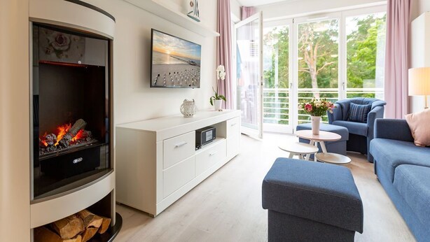 En moderne stue med pejs, sofaarrangement, sofabord og en balkon med gardiner.