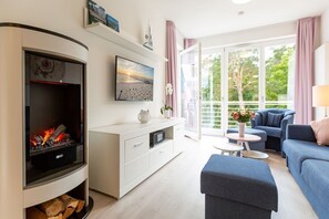 Una sala de estar moderna con chimenea, un conjunto de sofá, una mesa de centro y un balcón con cortinas.