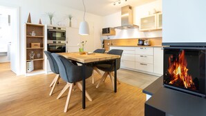 Una cocina moderna con una mesa de comedor, sillas, microondas, horno y chimenea.