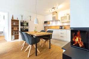 Une cuisine moderne avec une table à manger, des chaises, un four à micro-ondes, un four et une cheminée.