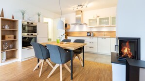Una cocina moderna con una isla central, horno empotrado, microondas y estufa de leña.