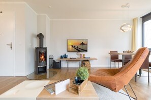 Uma sala de estar moderna com lareira, área de jantar e uma grande janela.