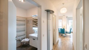 Et moderne badeværelse med bruser, toilet og vask, der fører til et spiseområde med stole og et bord.