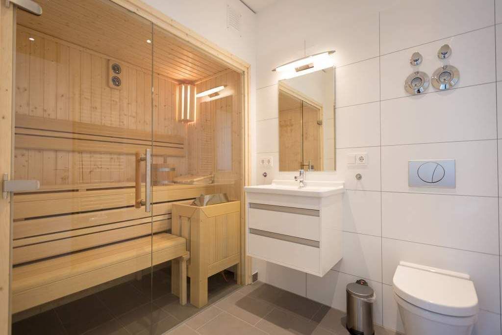 A modern bathroom with a wooden sauna, a sink, and a toilet.