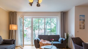 Ein modernes Wohnzimmer mit einer Couch, einem Sessel und einem kleinen Tisch mit einem Buch.