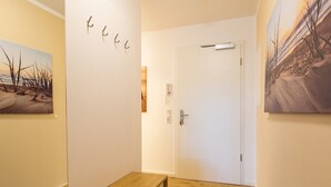 Ein Korridor mit einer Holzbank, einer Tür und zwei an der Wand hängenden Bildern.